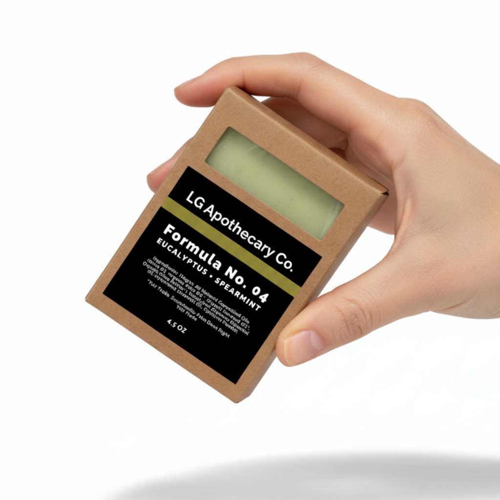 Hand holding a small LG Apothecary Co. product packaging on a white background