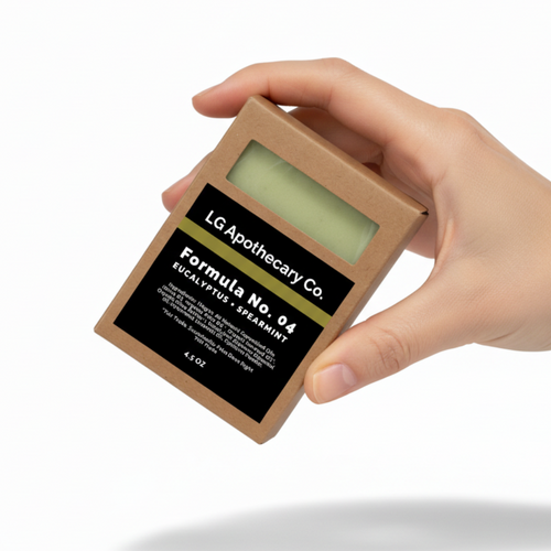 Hand holding a small LG Apothecary Co. product packaging on a white background