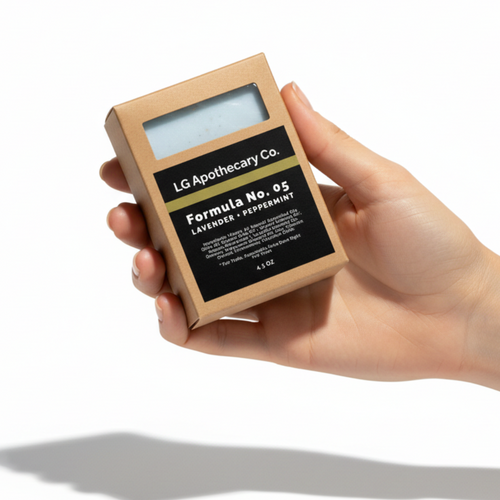 Hand holding a small cardboard box with 'LG Apothecary Co.' branding on a white background