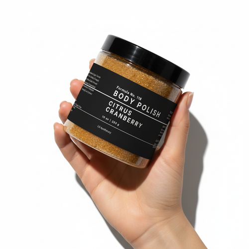 A hand holding a jar of Formula No. 118 Citrus Cranberry Body Polish against a white background with cinematic shadows.