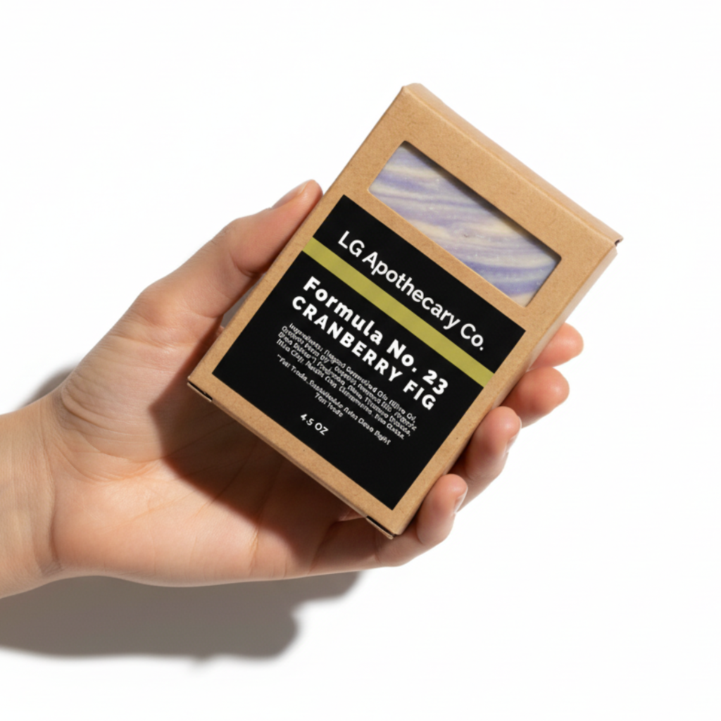 Hand holding a LG Apothecary Co. soap bar packaging on a white background